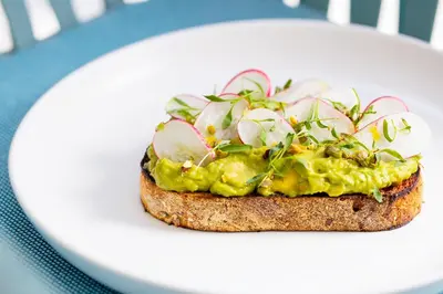 a piece of bread with avocado and apples on a plate at The Kimpton Shorebreak Fort Lauderdale Beach Resort in Fort Lauderdale