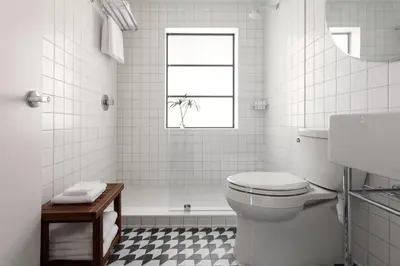 a white bathroom with a toilet and a bath tub at The Kimpton Shorebreak Fort Lauderdale Beach Resort in Fort Lauderdale
