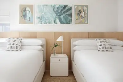 a bedroom with two beds and a nightstand between them at The Kimpton Shorebreak Fort Lauderdale Beach Resort in Fort Lauderdale