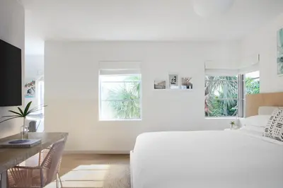 a white bedroom with a white bed and a desk at The Kimpton Shorebreak Fort Lauderdale Beach Resort in Fort Lauderdale