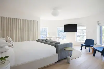 a bedroom with a bed and a couch and a tv at The Kimpton Shorebreak Fort Lauderdale Beach Resort in Fort Lauderdale