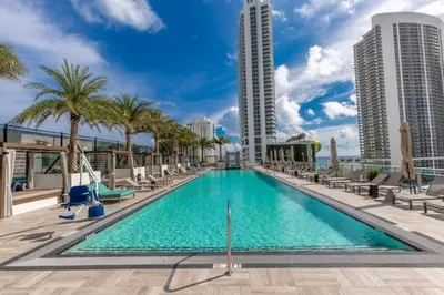 a swimming pool on the roof of a building with palm trees and buildings at Hyde Beach House Luxury Condo-Resort condo in Hollywood Beach