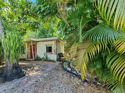 a small yellow house with a red door in a forest at The Rum Locker - 1 King - 2 Twins - Private home and Patio - Sleeps 4 in Fort Lauderdale