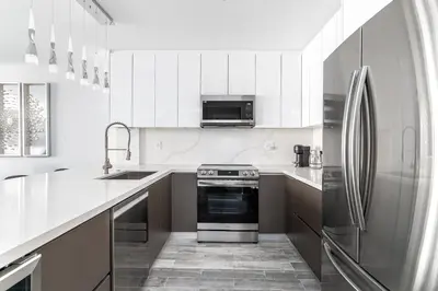 a kitchen with white cabinets and a stainless steel refrigerator at AMAZING 2BR 2BA NEWLY RENO BEACHFRONT APT W/BEACH VIEW in Hollywood