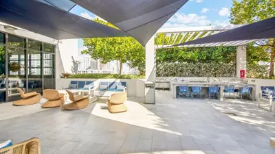 a patio with chairs and tables and an umbrella at Sentral Wynwood in Miami