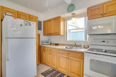 a kitchen with wooden cabinets and a white refrigerator at 2 Mi to Boardwalk Home with Grill in Dania Beach! in Dania Beach