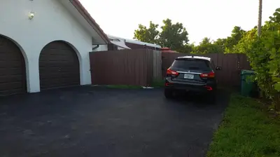 a car parked in a driveway next to a fence at Remodeled and Comfortable RV - FREE PARKING in Miami