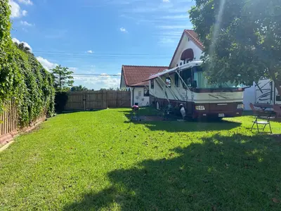 an rv parked in a yard next to a house at Remodeled and Comfortable RV - FREE PARKING in Miami