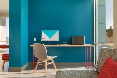 a desk with a computer on a blue wall at avid hotel - Ft Lauderdale Airport - Cruise by IHG in Fort Lauderdale