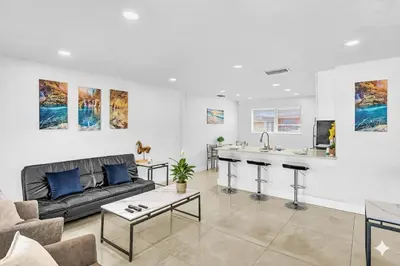 a living room with a couch and a kitchen at Modern 2br Near Aventura Mall & Sunny Beach in Hallandale Beach