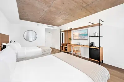 a bedroom with two beds and a desk at Upsun Hotel in Miami Beach