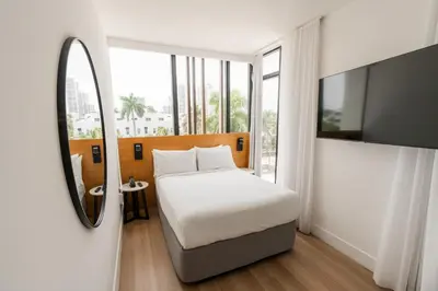 a bedroom with a bed and a mirror and a tv at Upsun Hotel in Miami Beach