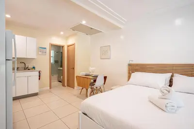 a bedroom with a white bed and a kitchen at Casa Del Mar Master in Hollywood