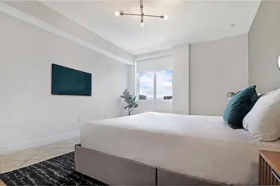 a white bedroom with a large bed and a flat screen tv at Roami at Sunny Isles in Miami Beach