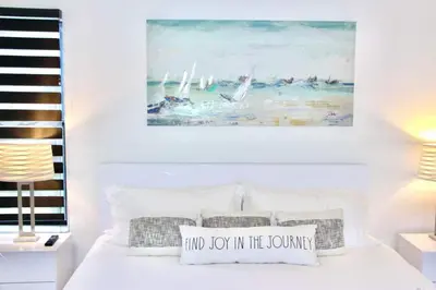 a bedroom with a white bed with a painting on the wall at Lux House Heated Spa & Free Boat Tour! in Fort Lauderdale