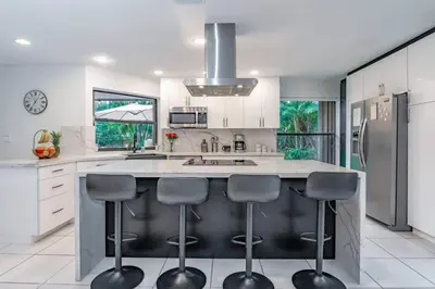 a kitchen with a large island with four bar stools at Lux House Heated Spa & Free Boat Tour! in Fort Lauderdale