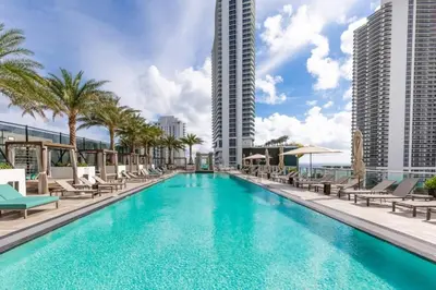 a pool with chairs and palm trees and buildings at Hyde Beach House Luxury Condo-Resort condo in Hollywood Beach
