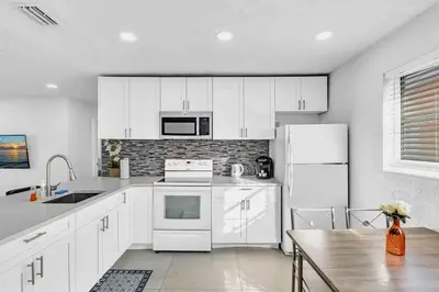 a kitchen with white appliances and a wooden table at 2 Bdrm Modern House Mins From Beach & Casino Hb1 in Hallandale Beach