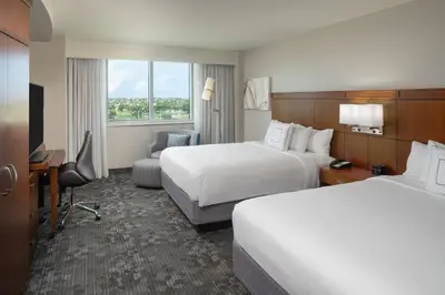 a hotel room with two beds and a desk at Courtyard by Marriott Miami Airport in Miami