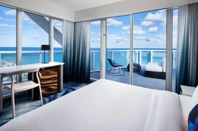 a bedroom with a bed and a desk with a view of the ocean at W Fort Lauderdale in Fort Lauderdale