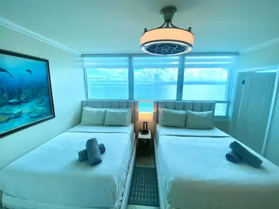 two beds in a room with a blue room at Castle Beach Resort Condo - Panoramic Large Penthouse or Deluxe 1 BR Direct Ocean View and beach access- Updated-Free parking- in Miami Beach