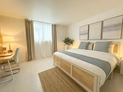 a bedroom with a large bed with a desk and a window at Amplio y moderno departamento con acceso directo a la playa in Hollywood
