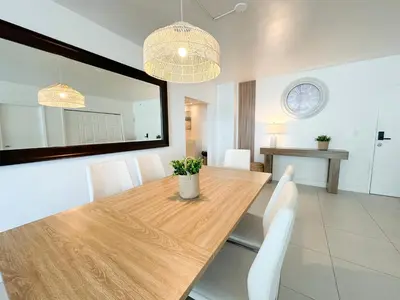 a dining room with a wooden table and white chairs at Amplio y moderno departamento con acceso directo a la playa in Hollywood