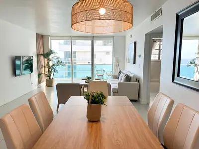 a dining room and living room with a table and chairs at Amplio y moderno departamento con acceso directo a la playa in Hollywood