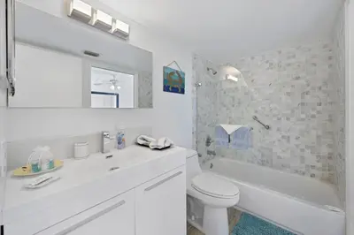 a white bathroom with a toilet and a tub and a sink at Yacht Club at aventura Amazing Marina view parking included in Miami