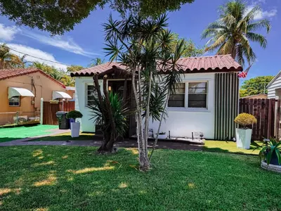 a house with a palm tree in the yard at Hammocks & mini-golf! 10 mins from Beach! in Hollywood