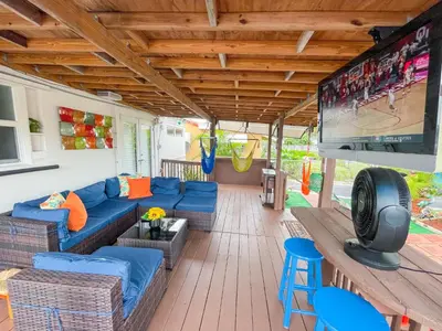 a living room with blue couches and a flat screen tv at Hammocks & mini-golf! 10 mins from Beach! in Hollywood