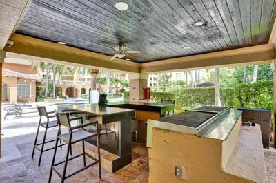 an outdoor kitchen with a bar and stools at Renovated cozy The yacht club at aventura Parking included in Miami
