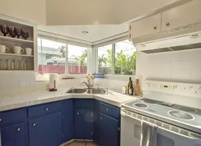 a kitchen with blue cabinets and a sink and a window at Surf House - Paddleboards - Canoes -1 mile to Wilton Manors in Fort Lauderdale