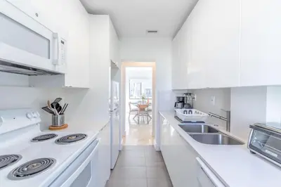 a white kitchen with a sink and a stove at Renovated Apts with Kitchen, Fast WiFi, Smart TV, Roku & Pool Onsite 4 mi to Surfside Beach in North Miami