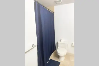 a bathroom with a toilet and a blue shower curtain at Comfortable 2 BR at Brickell , Free Parking in Miami