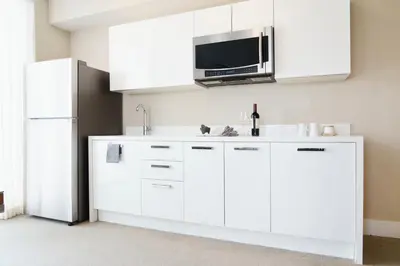 a kitchen with white cabinets and a microwave and a refrigerator at The Altair Bay Harbor Hotel in Miami Beach