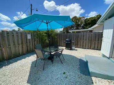 a table and chairs with a blue umbrella in a backyard at Home wworkstation by PMI unit 2908 in Hollywood