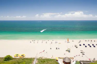 a beach with chairs and umbrellas and the ocean at Fort Lauderdale Marriott Harbor Beach Resort & Spa in Fort Lauderdale