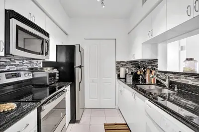a kitchen with a sink and a refrigerator at Yacht Club Newly renovated parking included in Aventura
