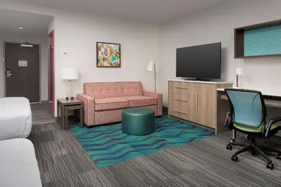 a hotel room with a couch and a television at Home2 Suites By Hilton Miami Airport South Blue Lagoon in Miami