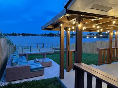 a pavilion with a couch on a deck near the water at SuperVilla - Lakefront - Sunsets, Kayaks, Grill in Fort Lauderdale