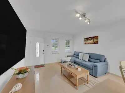 a living room with a blue couch and a table at SuperVilla - Lakefront - Sunsets, Kayaks, Grill in Fort Lauderdale