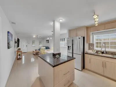a large kitchen with a refrigerator and a counter top at SuperVilla - Lakefront - Sunsets, Kayaks, Grill in Fort Lauderdale