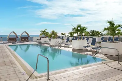 a swimming pool with chairs and the ocean in the background at Hilton Cabana Miami Beach Resort in Miami Beach