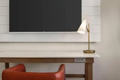 a desk with a television on a wall with a chair at Hilton Cabana Miami Beach Resort in Miami Beach