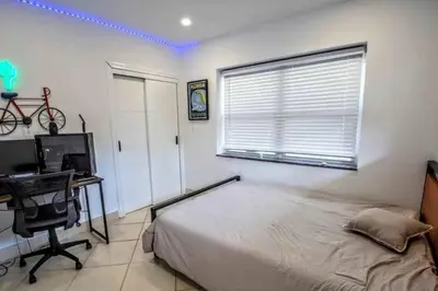 a bedroom with a bed and a desk with a computer at SWAYING PALM BEACH HOUSE Walk to Beach , Marina, Port, las Olas in Fort Lauderdale