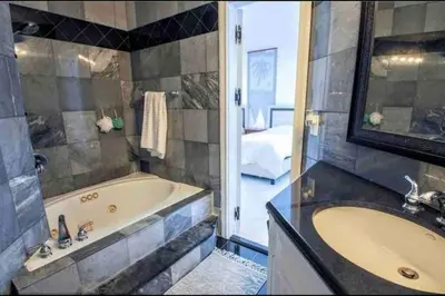 a bathroom with a tub and a sink and a mirror at SWAYING PALM BEACH HOUSE Walk to Beach , Marina, Port, las Olas in Fort Lauderdale