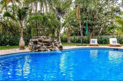 a swimming pool with two chairs and a rock slide at SWAYING PALM BEACH HOUSE Walk to Beach , Marina, Port, las Olas in Fort Lauderdale