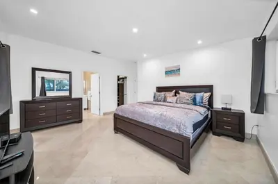 a bedroom with a bed and two dressers and a television at Pool Villa in Miami