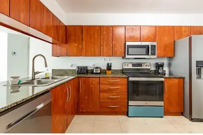 a kitchen with wooden cabinets and a stove and microwave at Two Bedroom Oceanview Apartment in Brickell in Miami